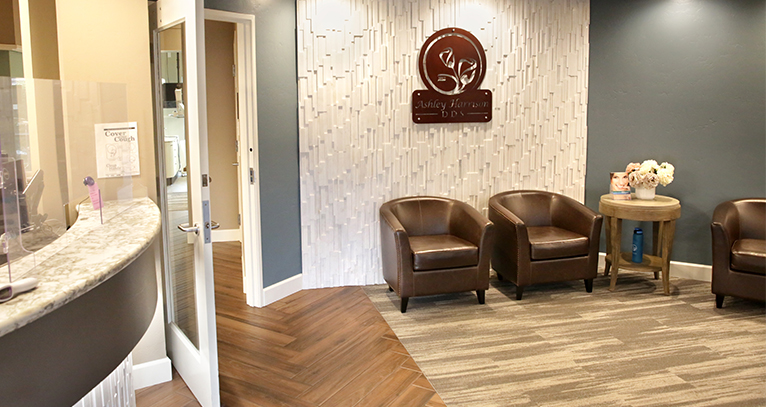 A photo of our lobby shows brown leather chairs seated around the exterior wall. Teal and white walls with hardwood flooring.
