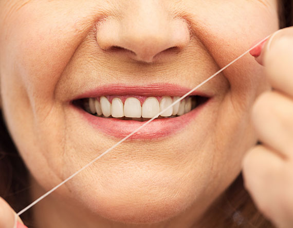 an up close photo of a woman's mouth as she flosses