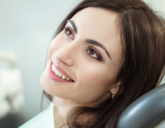 a middle aged woman sits in the dental chair and is smiling