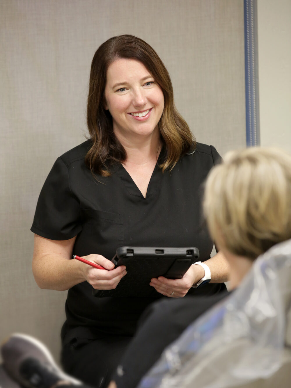 Dentist discussing treatment options with a patient using a tablet during a dental consultation.