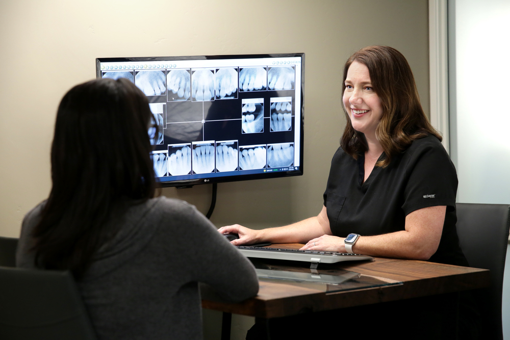 Dr. Ashley Harrison sitting with patient reviewing x rays as a part of the root canal treatment process