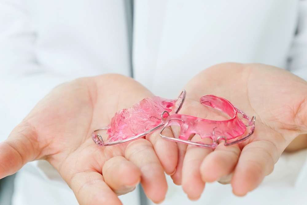 person holding a traditional Hawley retainer showcasing differences in night guard vs retainer
